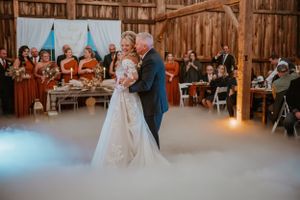 Romantic dance moment surrounded by fog effects in rustic barn wedding venue.