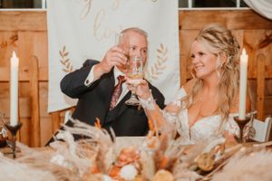 Celebratory toast at rustic barn wedding reception with autumn decor.
