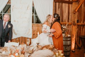 A rustic barn wedding ceremony with wooden decor and fall pumpkins.