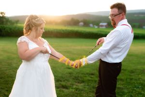 A couple shares a playful moment with lemons in their wedding attire against a rural backdrop.