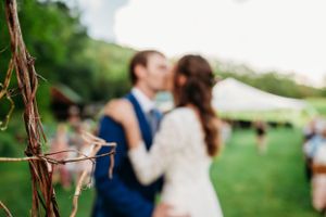 Blurred romantic moment between couple at outdoor wedding reception.