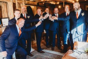 Group in formal attire raises glasses for celebratory toast at rustic venue.