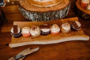 Artisanal cupcakes arranged on a rustic wooden serving board with natural bark edge.