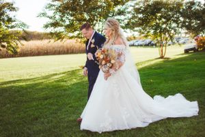Newlyweds walking together on a sunlit lawn during golden hour.