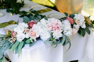 Elegant floral table decoration with pink roses, white peonies and green eucalyptus leaves.