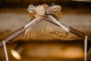 Gold 'Mrs. Wilson' wedding dress hanger decorated with white and gold flowers.