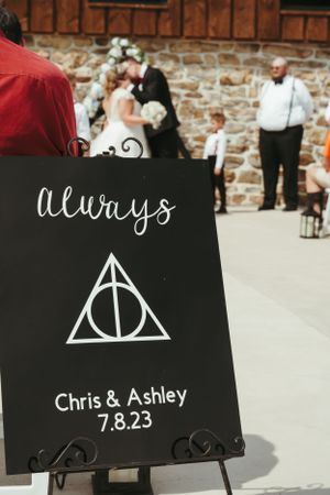 A black wedding sign featuring the Deathly Hallows symbol from Harry Potter with text reading 'Always' and a wedding date.