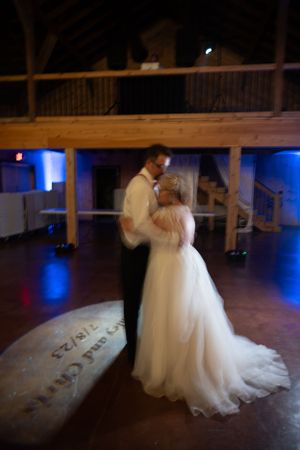 Couple sharing first dance in rustic barn venue with blue uplighting.
