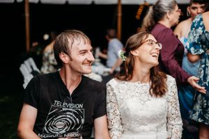 Couple shares joyful moment during wedding reception under outdoor tent.