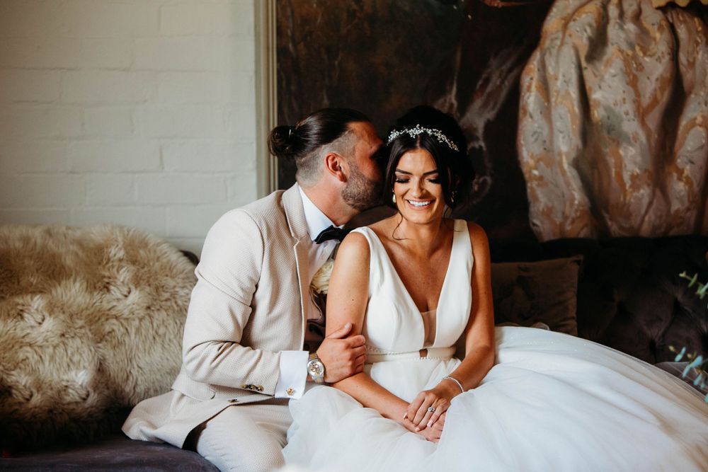 Tender candid moment between couple in elegant wedding attire.