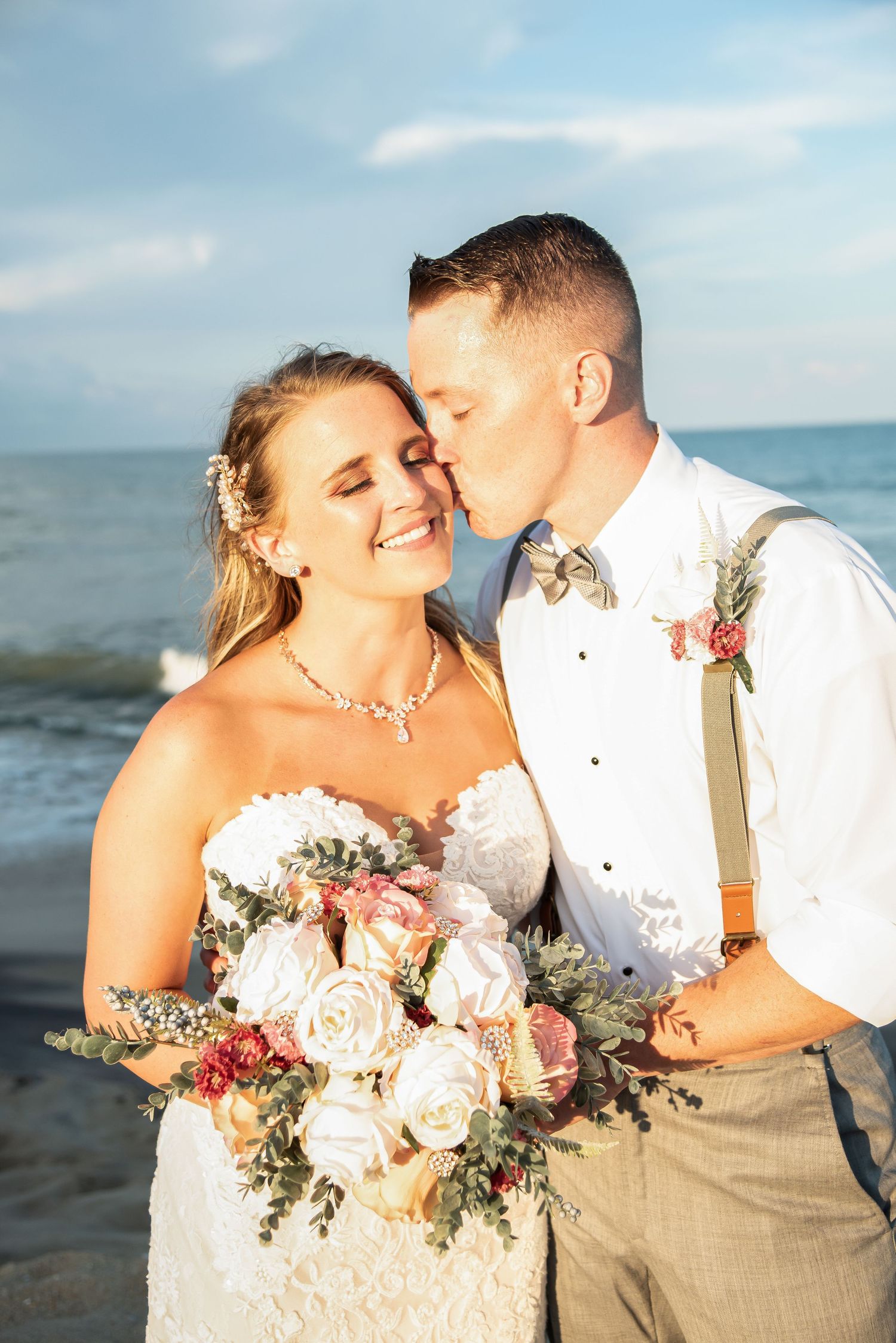 A beachside wedding portrait with soft lighting and a beautiful bouquet of blush roses.