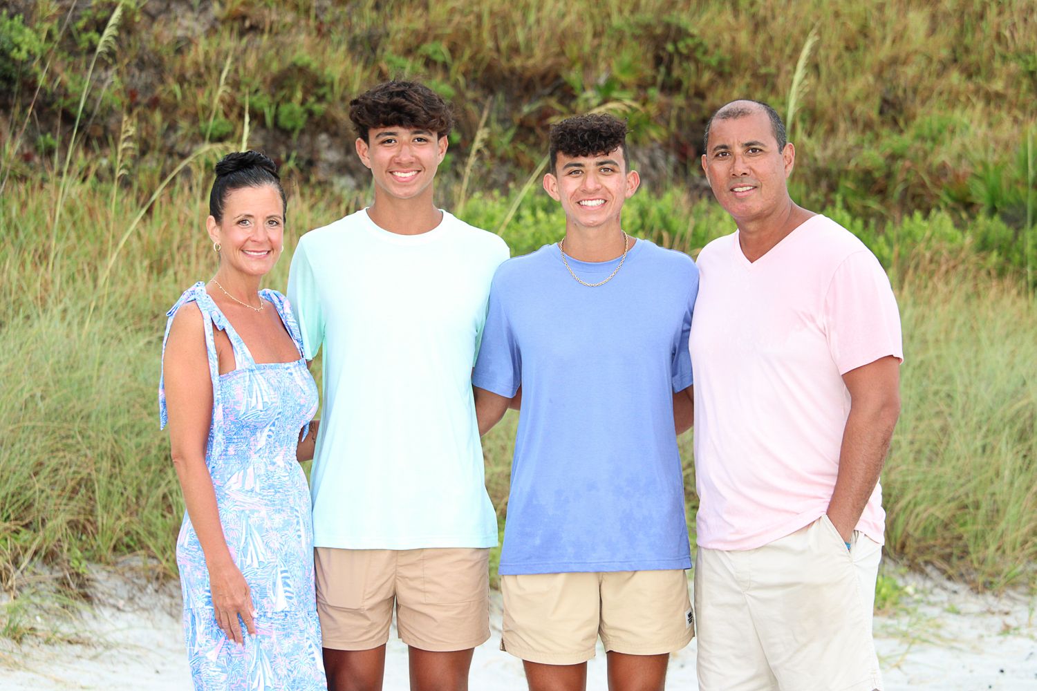 Casual group portrait on sand dunes with sea grass and coastal vegetation.