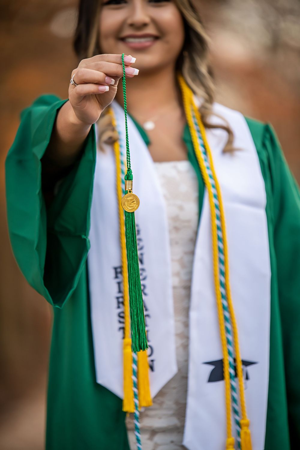 Close-up of graduation stole and honor cords on emerald green graduation gown.