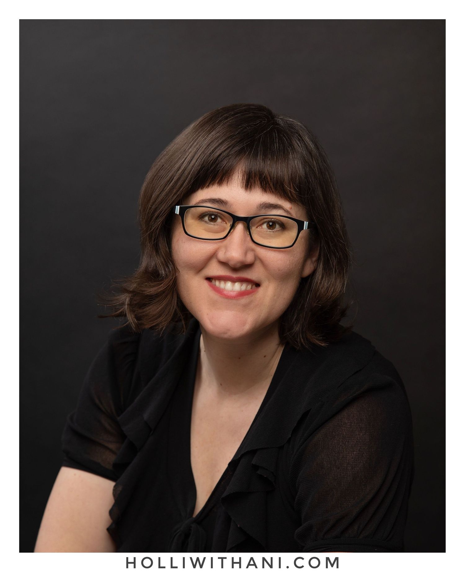 Studio Portrait of Woman wearing glasses and black blouse with black backdrop