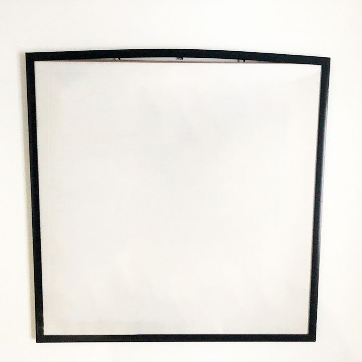 Large empty black square frame mounted on white wall.