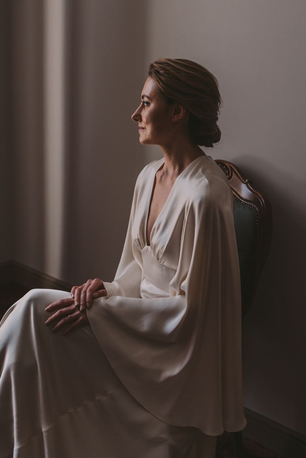 Elegant white wedding dress with flowing sleeves captured in dramatic indoor lighting.