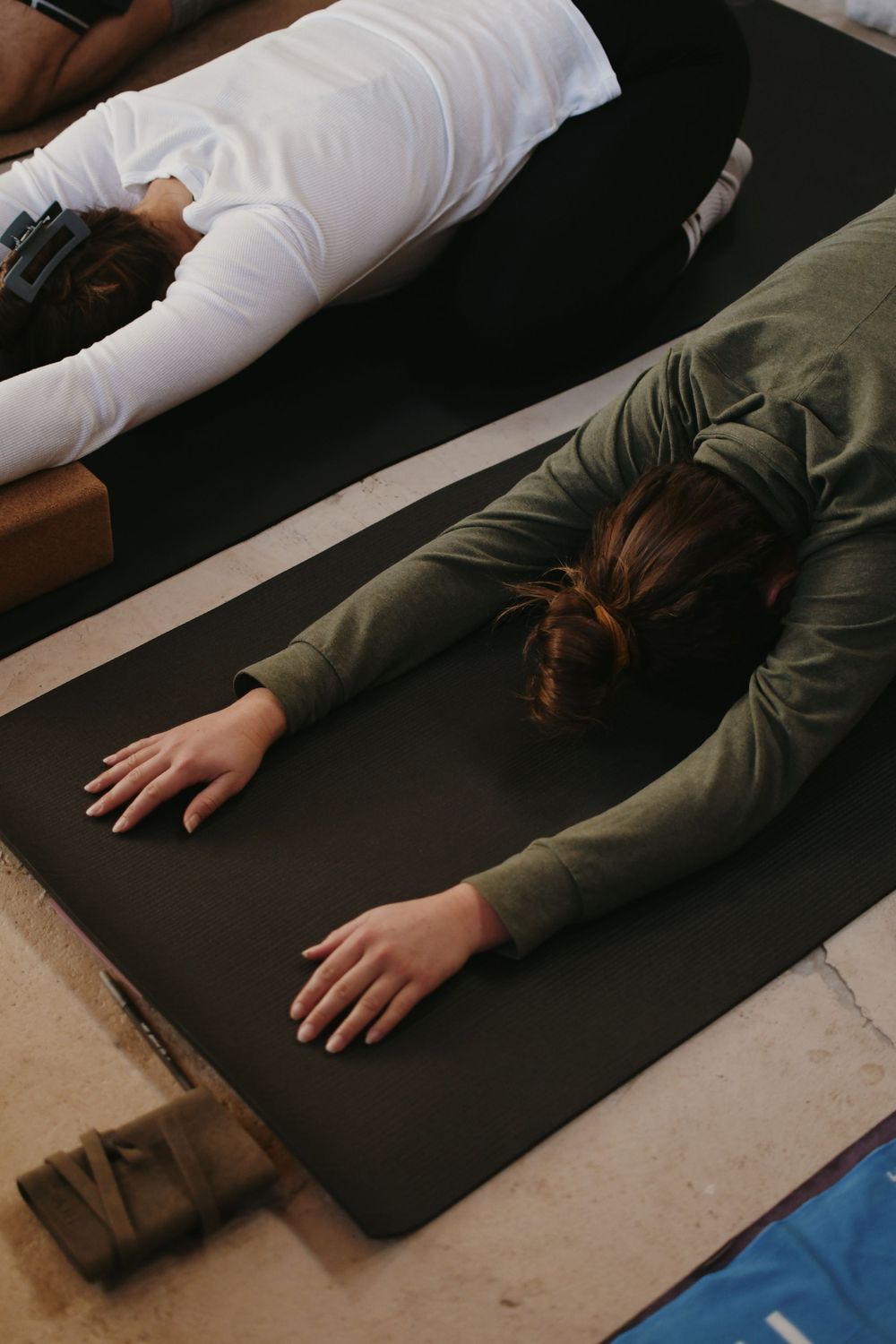 Person lying down on black yoga mat during relaxation exercise.