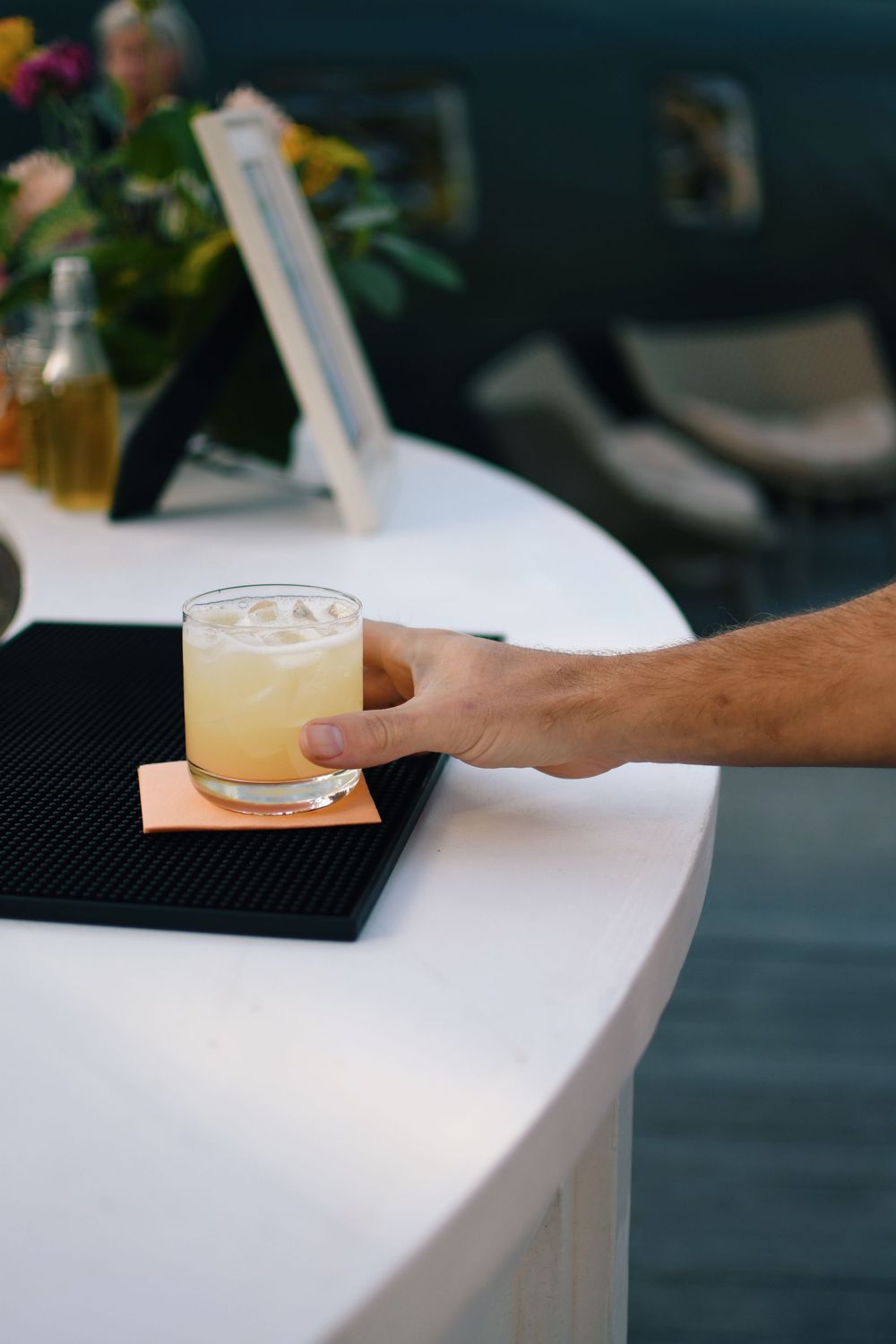 A drink being served on a white bar counter with soft focus background.