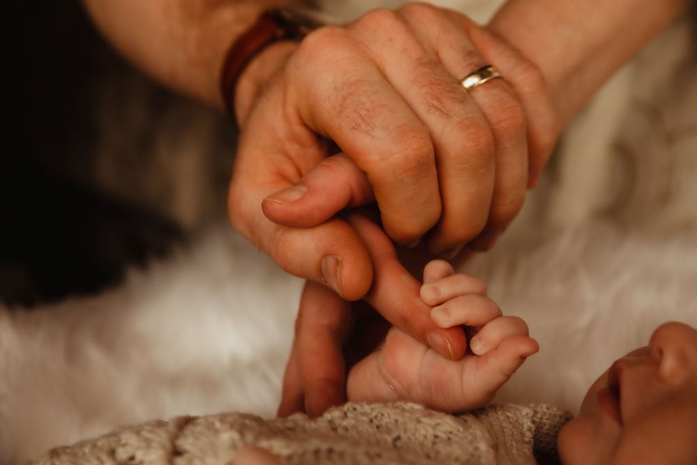 Newborn baby holds parents's hands