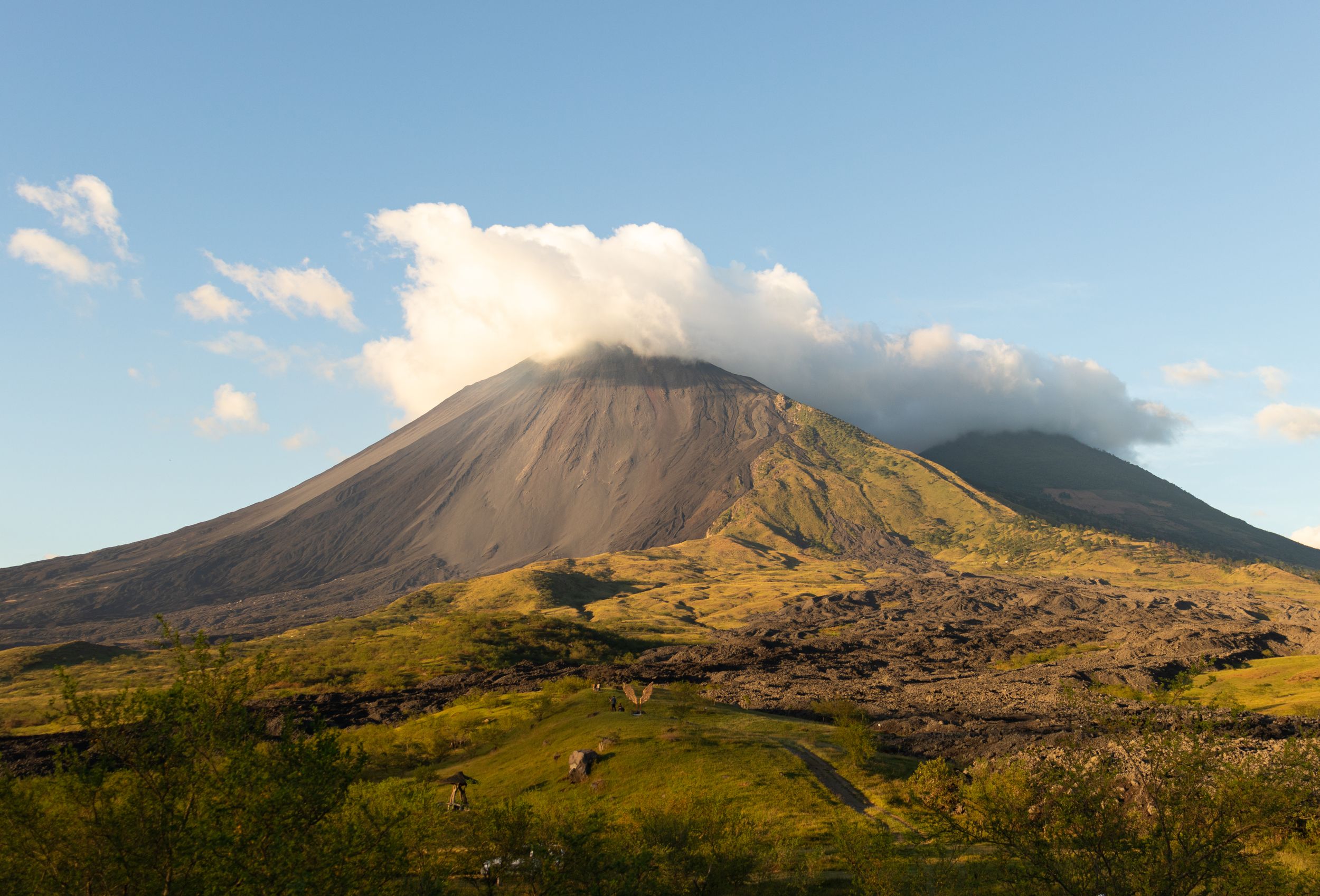 Scenic volcanic mountain range under blue sky with white puffy clouds.