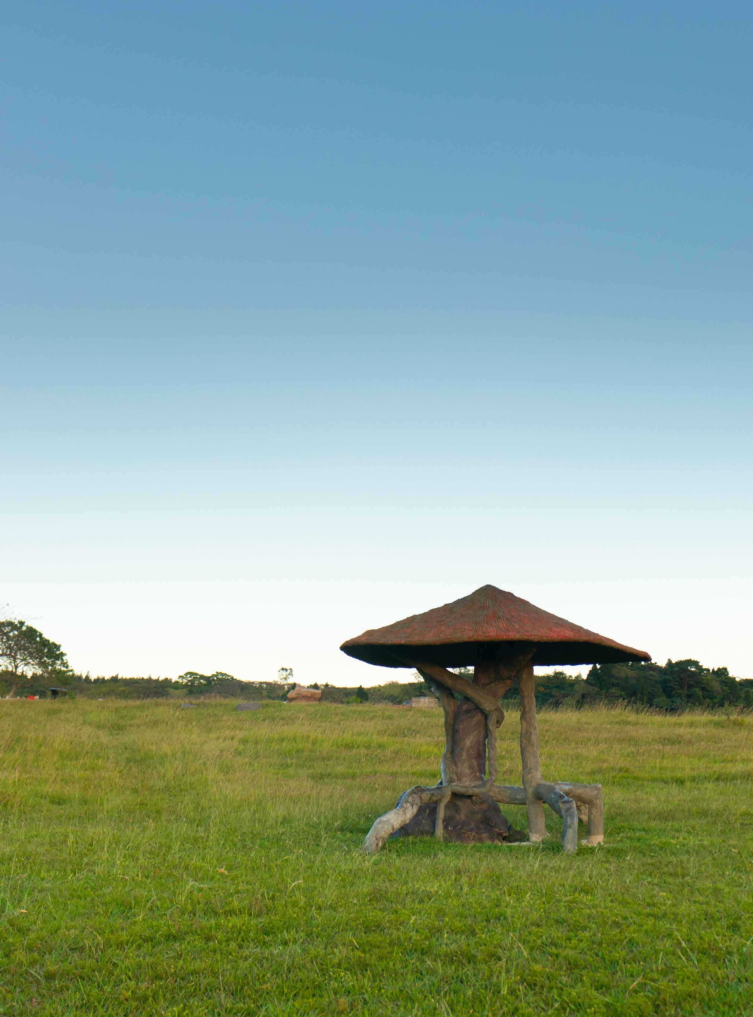 Historic megalithic dolmen monument standing in a green field under clear blue skies.