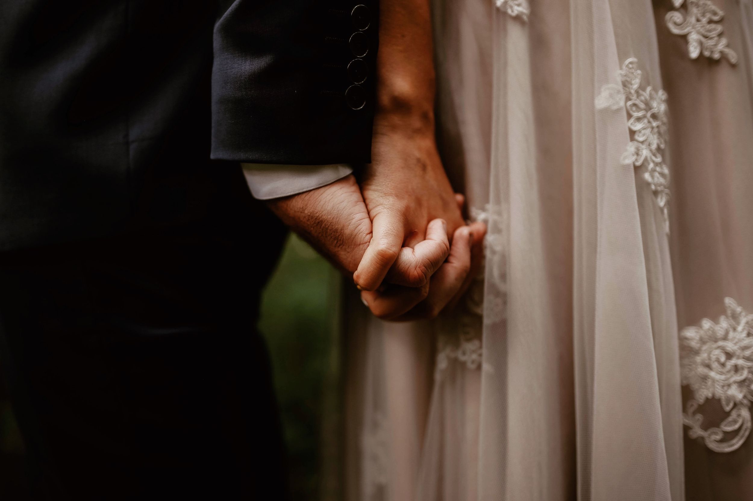 Close-up detail of hands holding each other against a light fabric background.