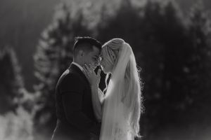 Scenic mountain wedding ceremony with evergreen trees and dramatic cloudy skies in the background.