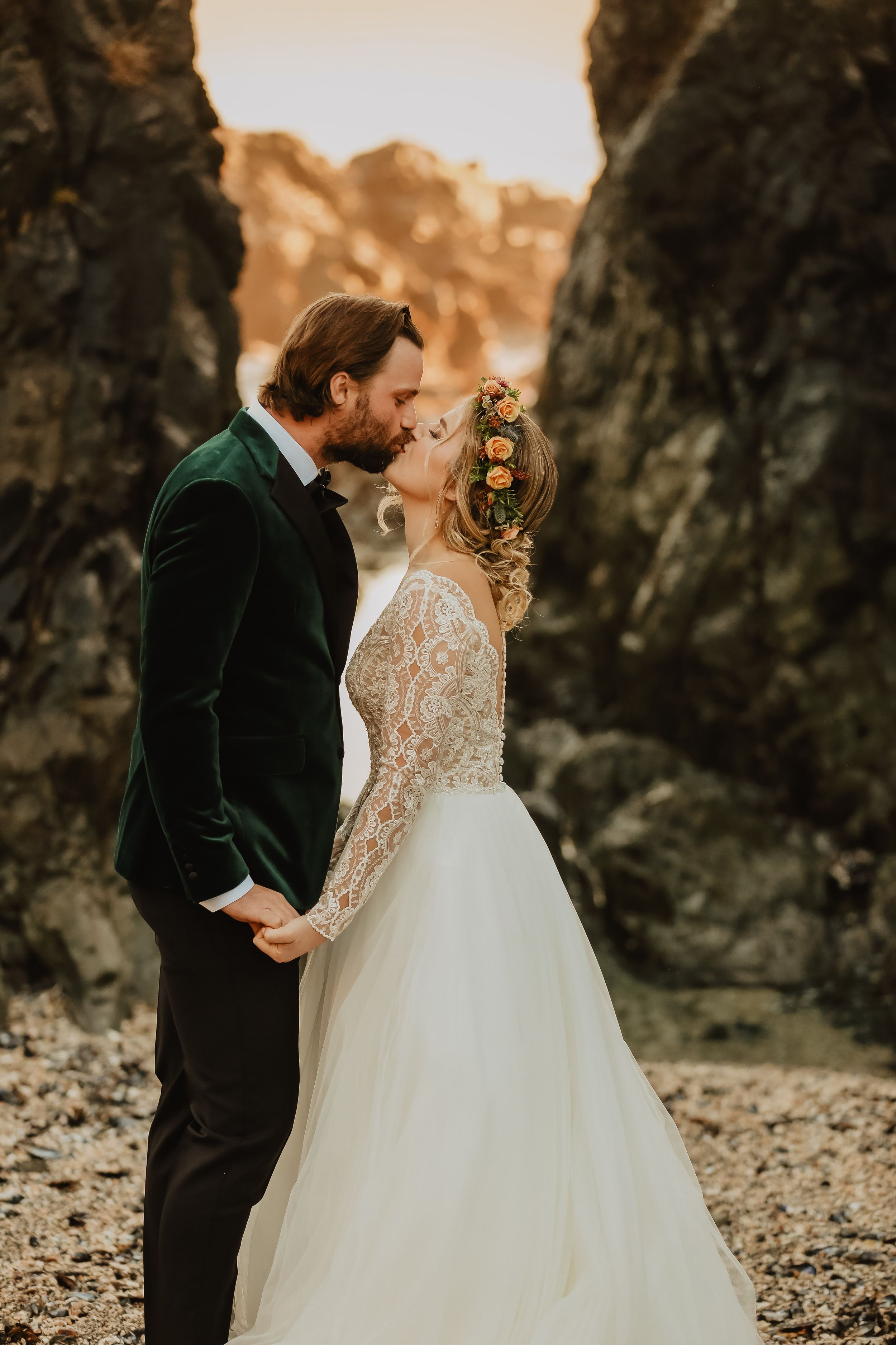Romantic sunset moment between couple against dramatic rocky cliffs.