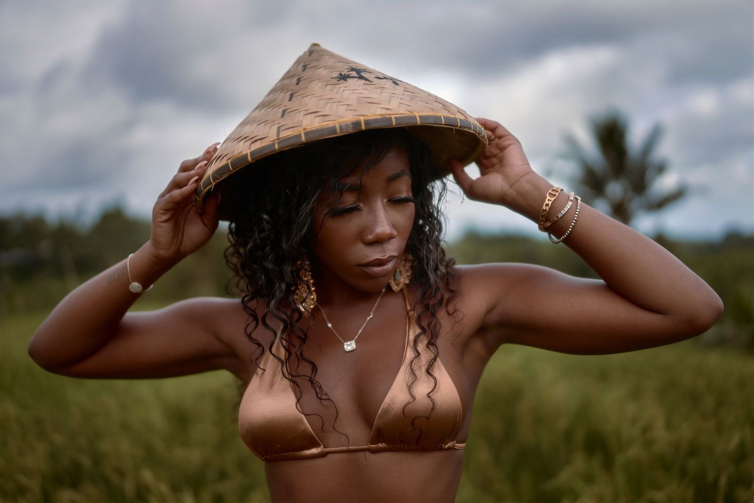 Portrait wearing conical hat against lush tropical background in natural lighting.