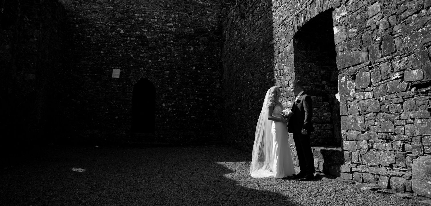 Black and white wedding photo showing couple in stone doorway of historic building.