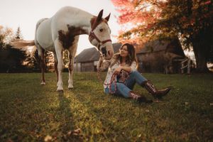 Peaceful autumn scene with white horse and rider relaxing on grass at sunset.