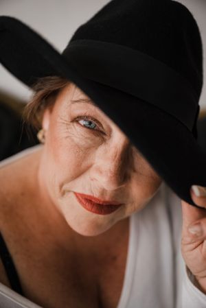 Dramatic close-up portrait wearing a black fedora hat and bold red lipstick.