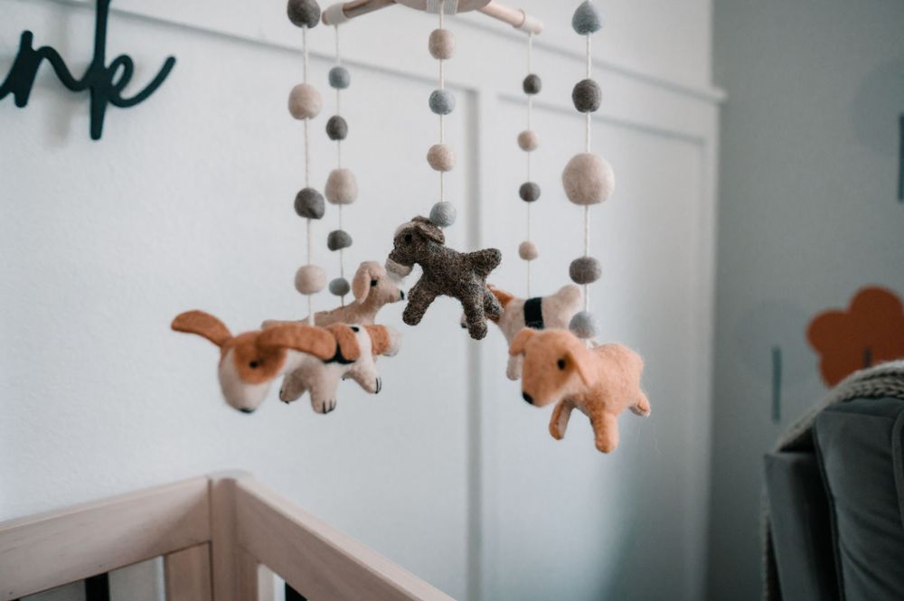 Soft orange and white nursery mobile with hanging decorations above crib.