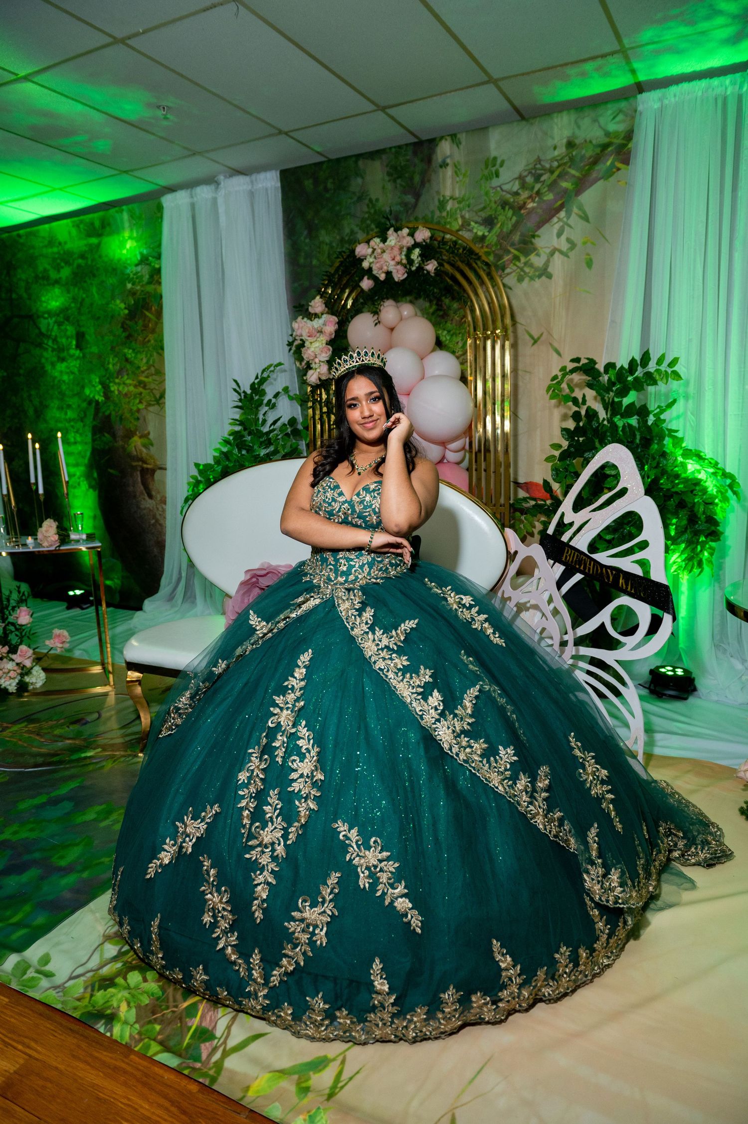 Elegant emerald green ballgown with gold embroidery details in a dreamy venue with green lighting.