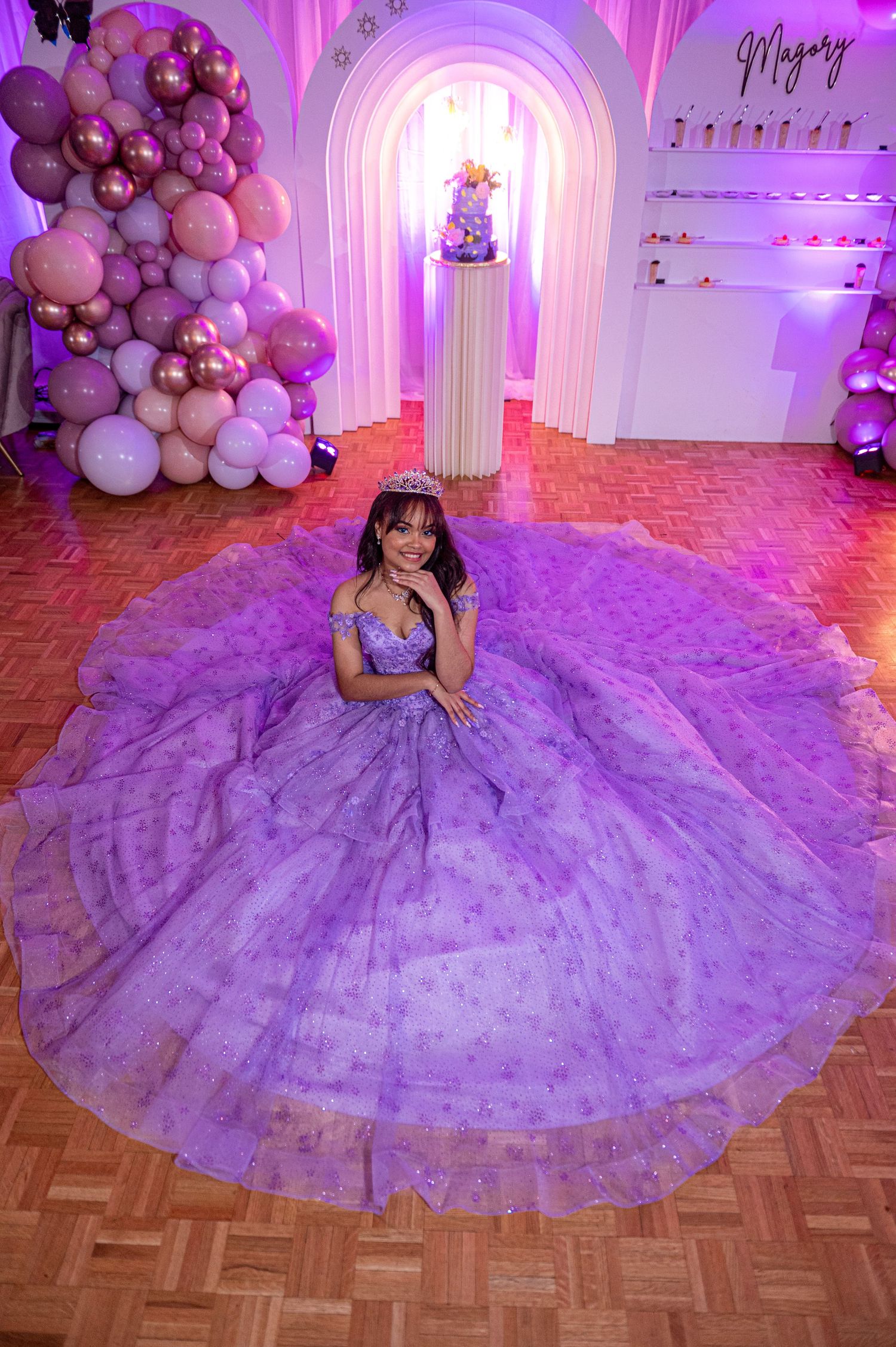 Lavender princess ball gown with sparkling details photographed in a pink-lit venue with balloon decor.
