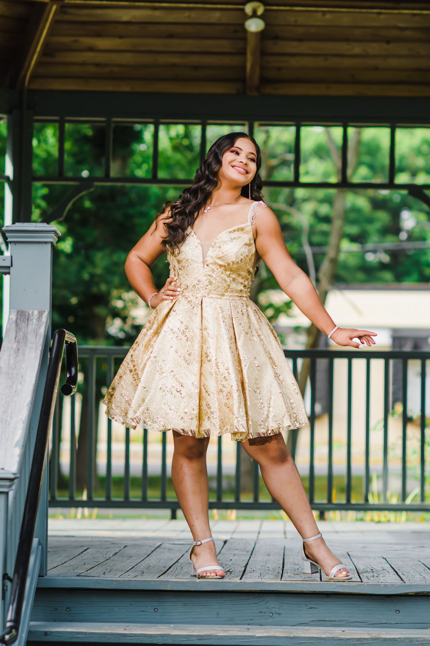 A sparkling gold cocktail dress photographed in an outdoor gazebo setting.