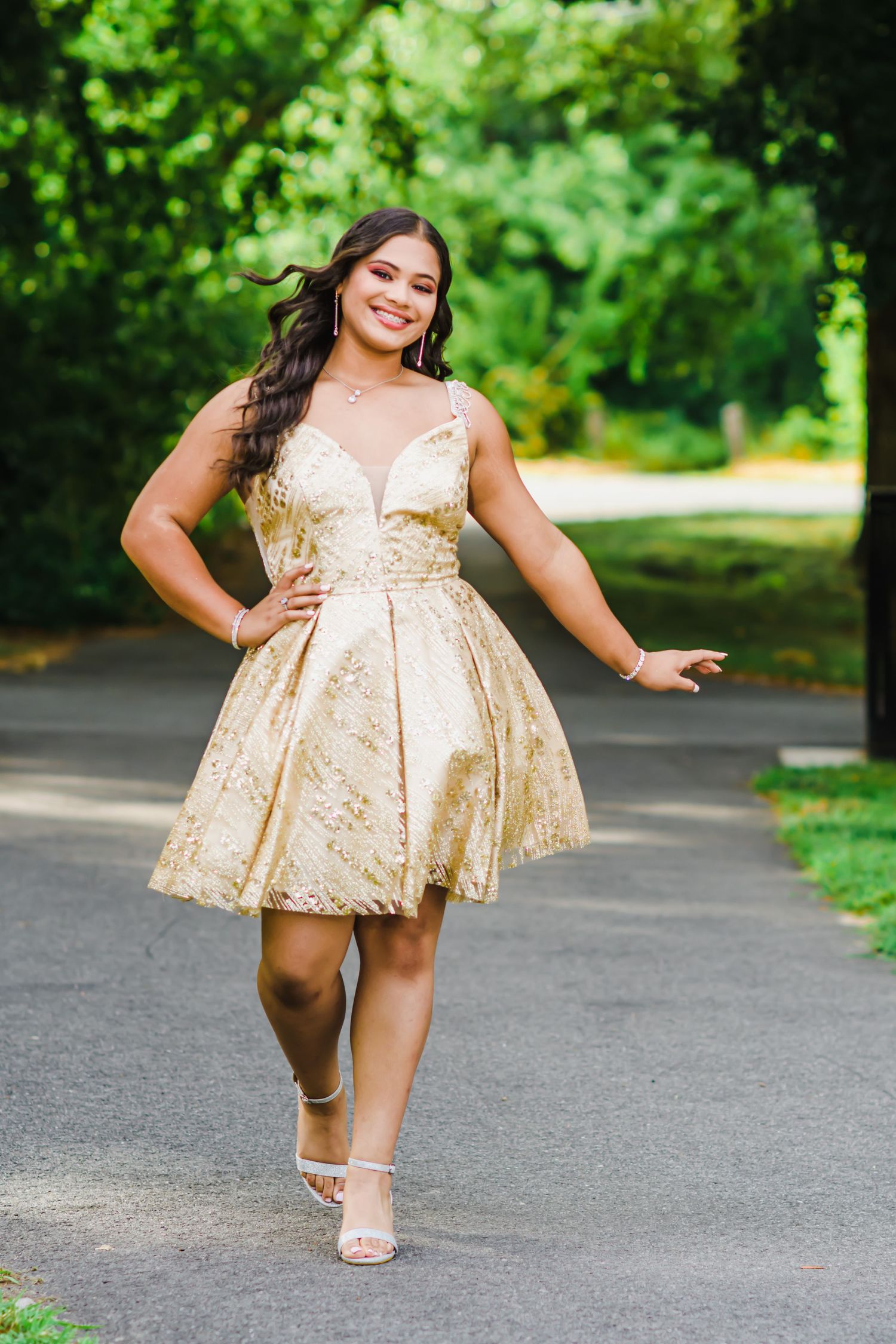 A short champagne-colored party dress photographed on a tree-lined pathway.