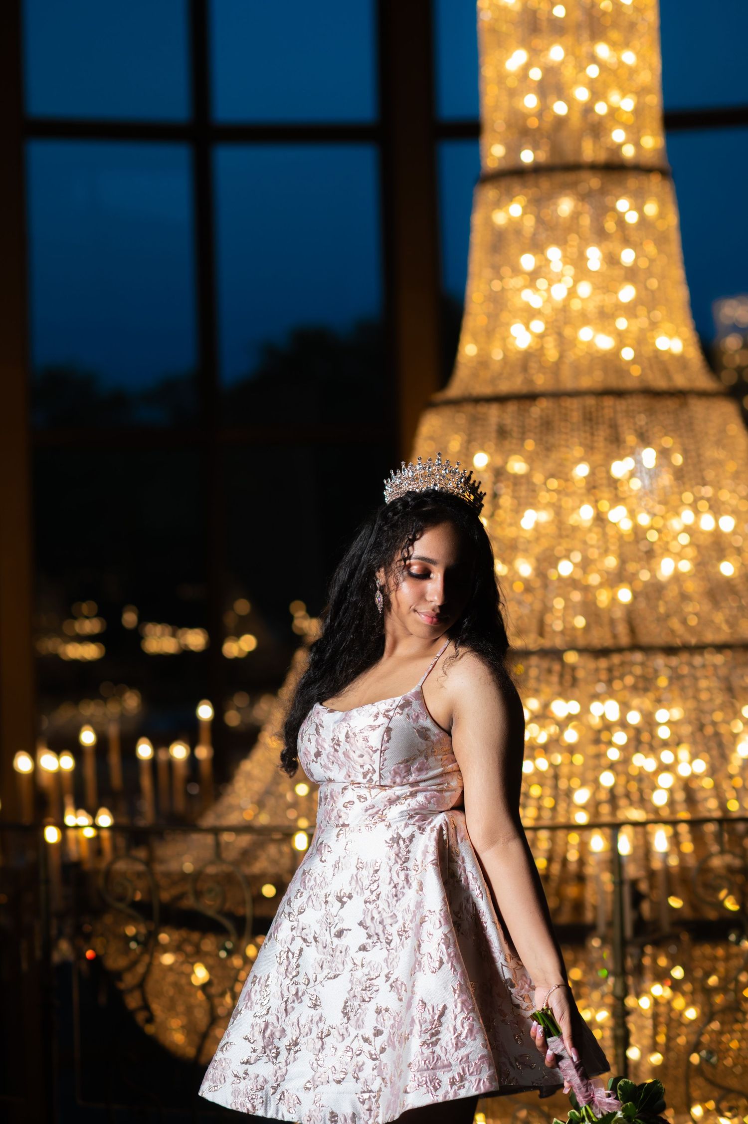 Sparkling cocktail dress photographed against illuminated Eiffel Tower replica at night.