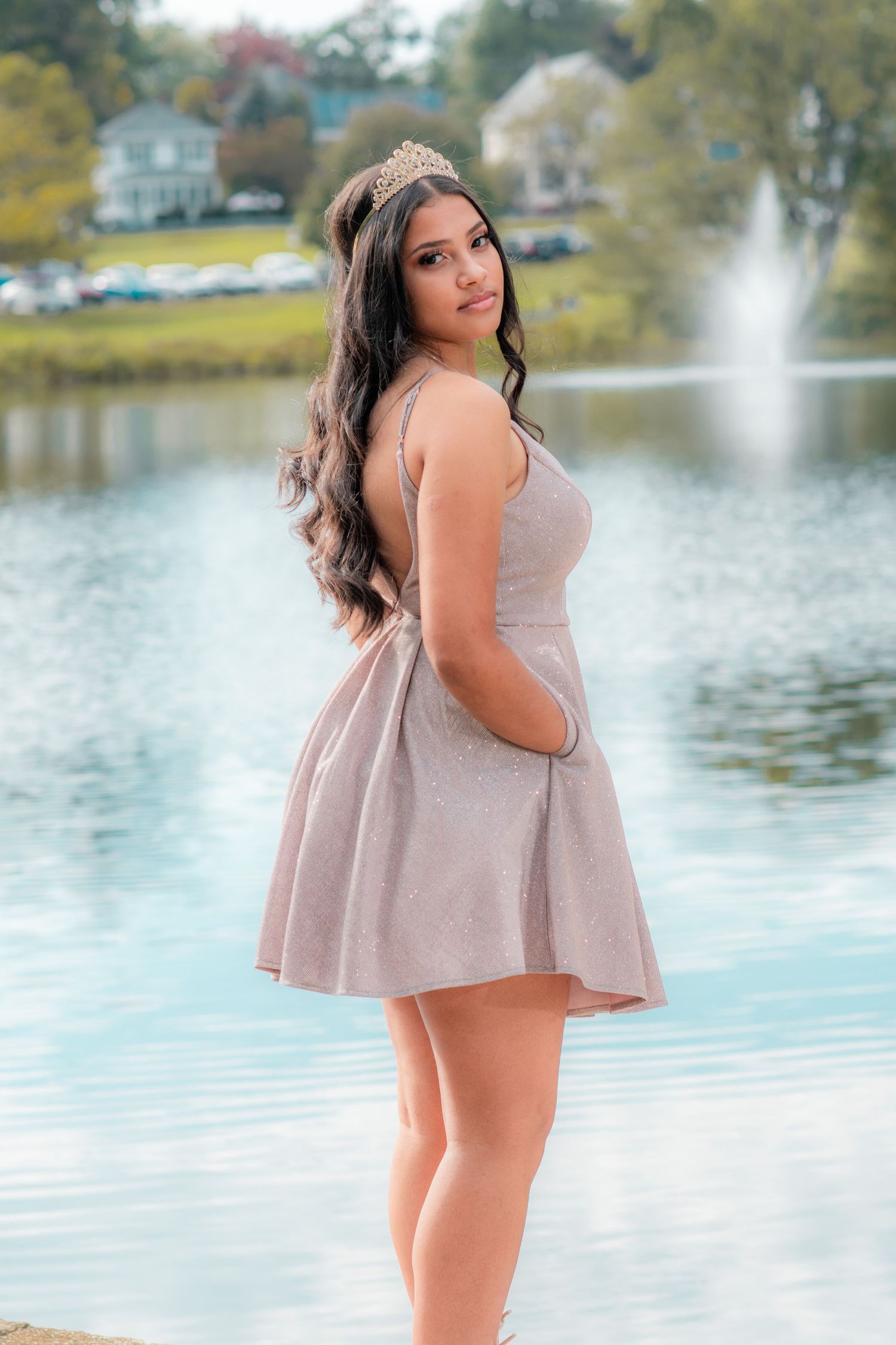 Model in pink babydoll dress poses gracefully by a serene lake during an autumn photoshoot.
