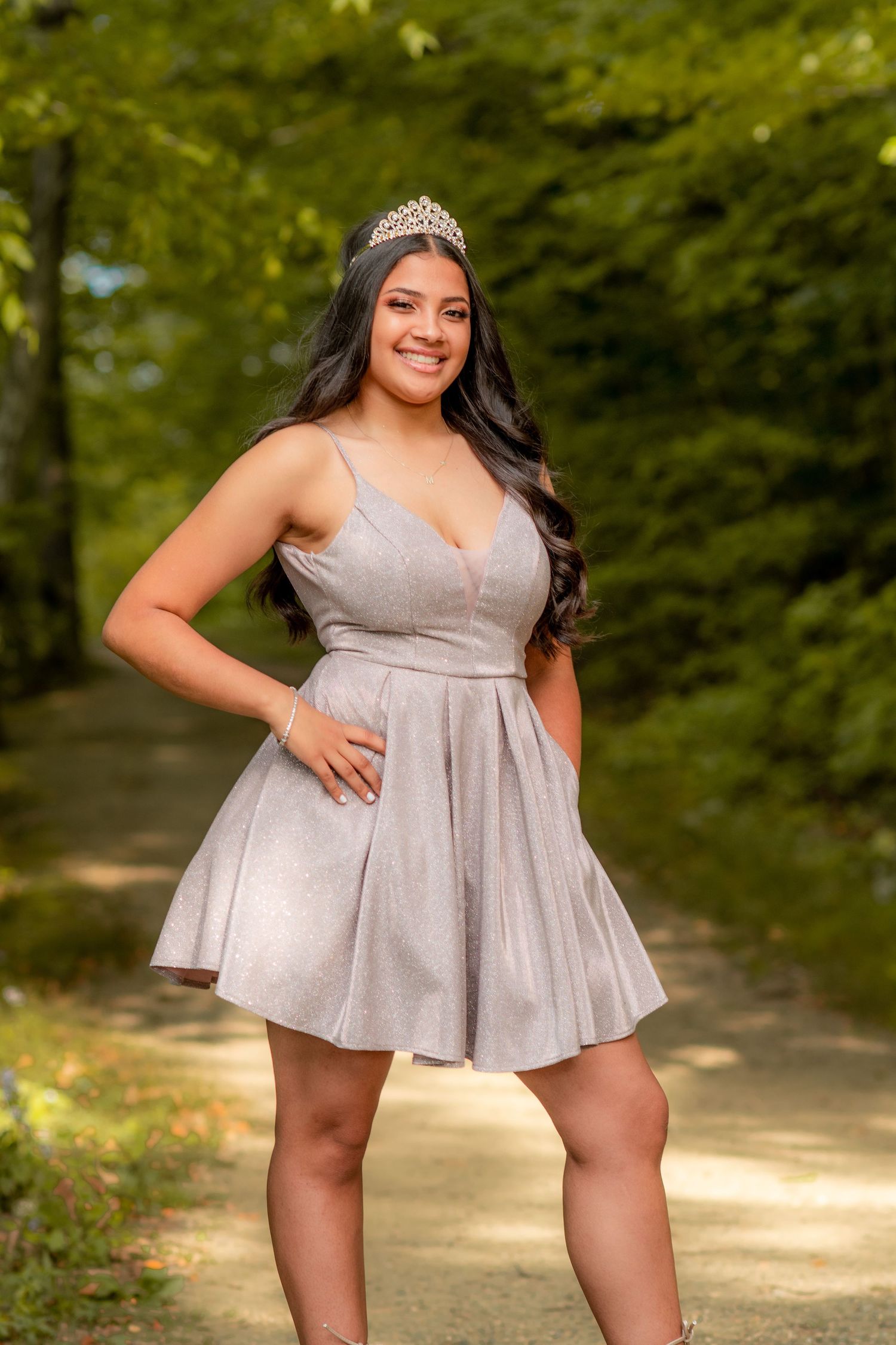 Outdoor portrait session showcasing a shimmering mini dress and tiara in a wooded setting.