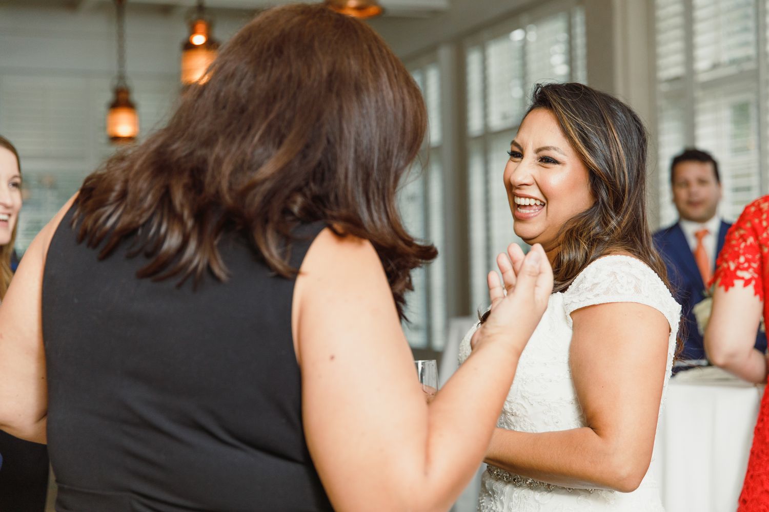 Wedding guests celebrate and dance during a reception in a bright indoor venue.