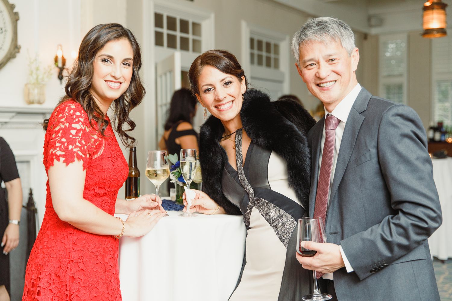 Guests enjoying drinks and conversation at an elegant indoor reception with warm lighting.
