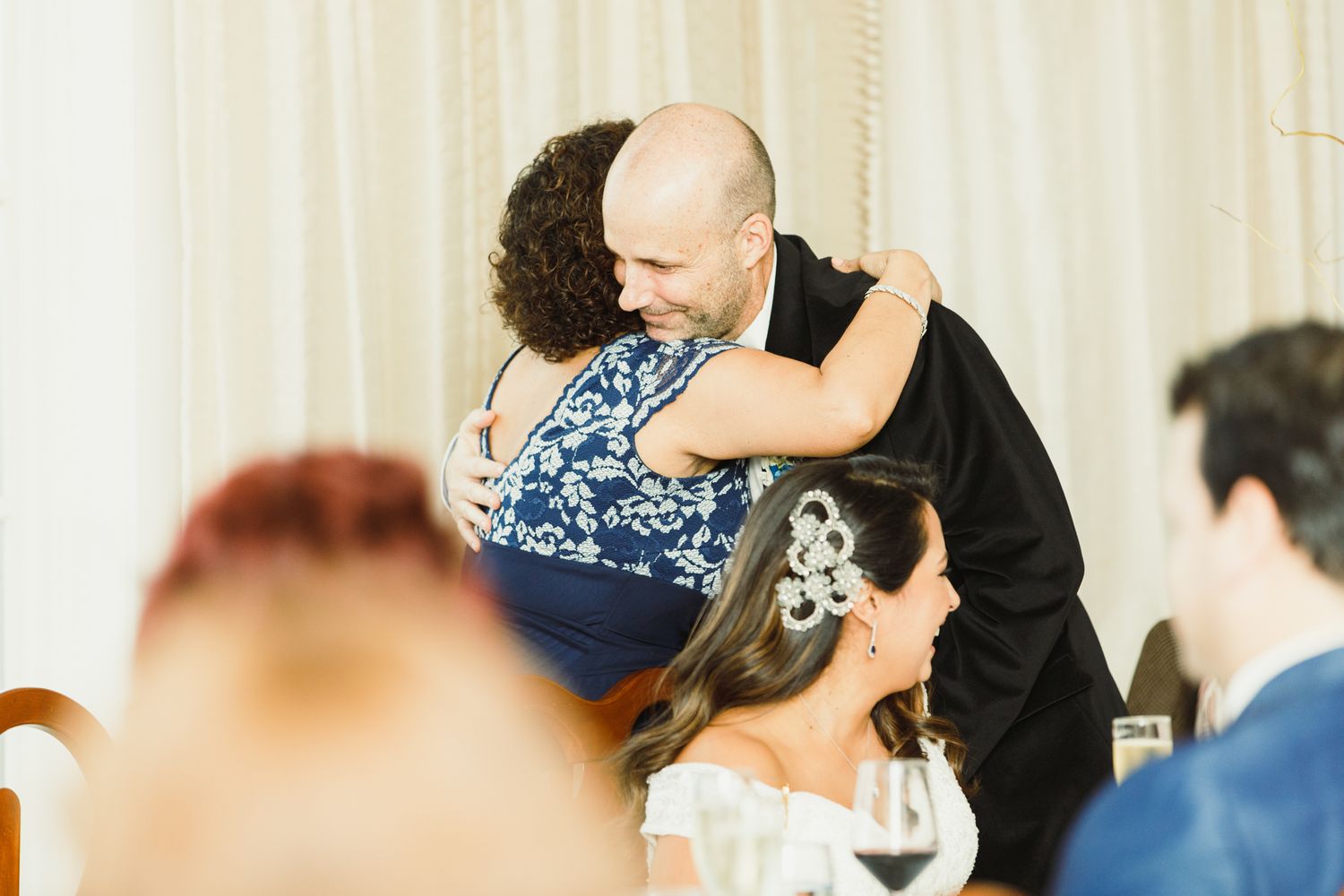 A warm embrace shared during a celebratory moment at an indoor event.