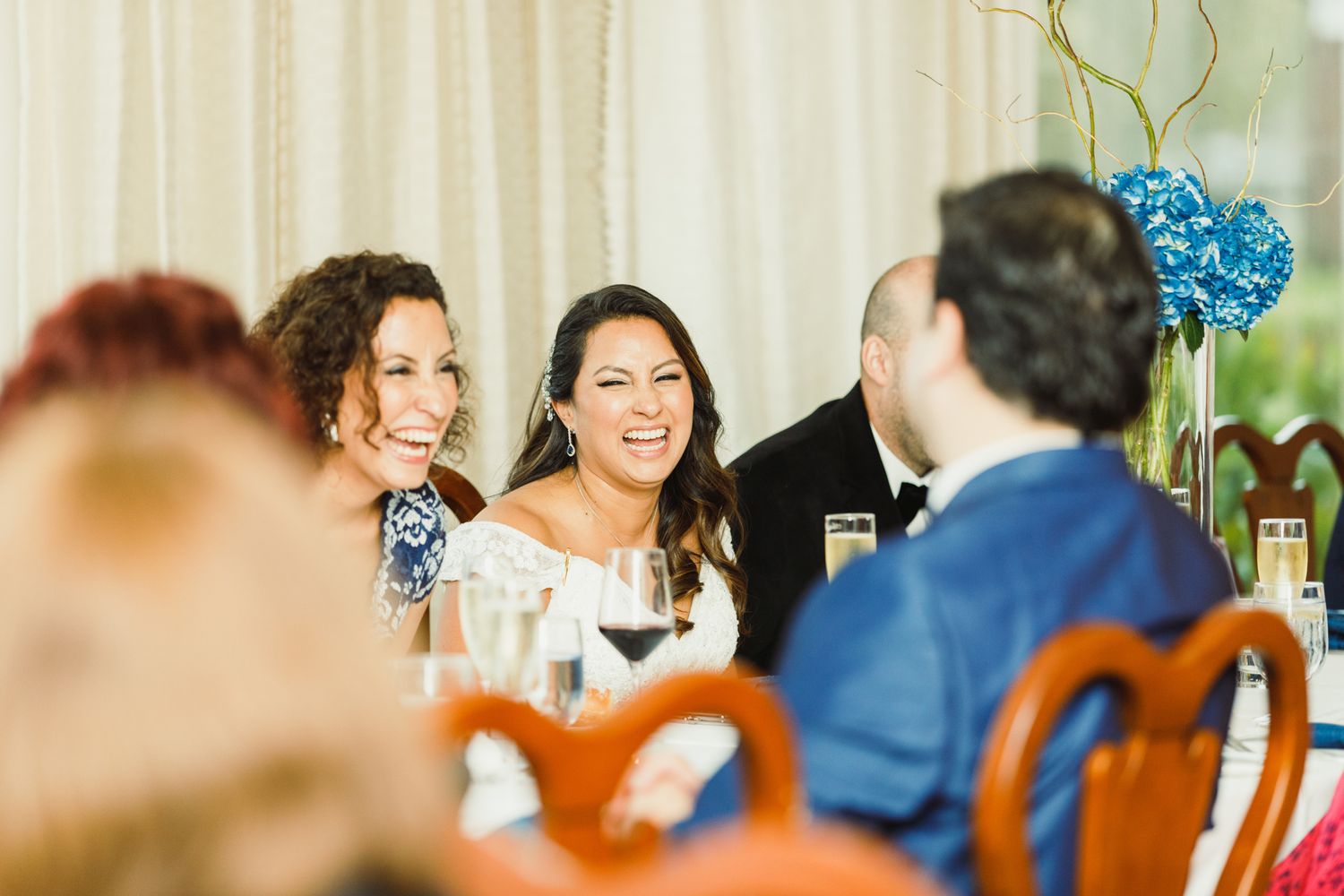 Guests sharing laughter and conversation at an elegant table setting with blue floral centerpieces.