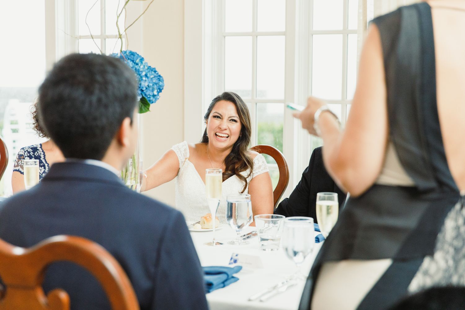 Guests seated at round tables decorated with blue accents during a formal celebration.