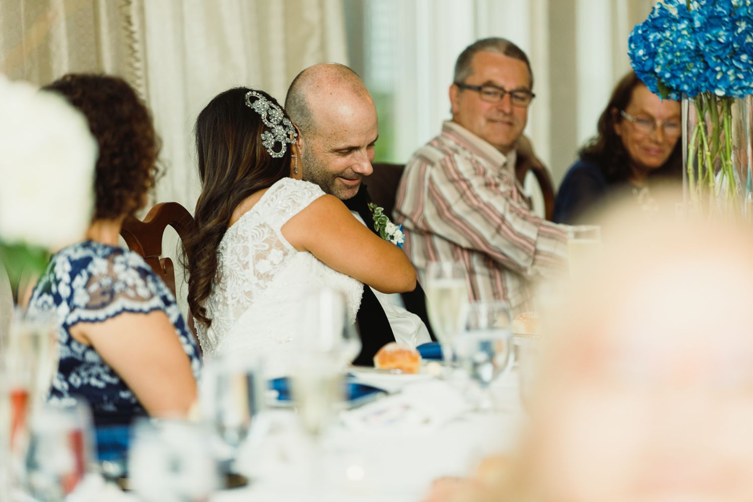 Candid moments captured during a celebratory dinner with blue floral centerpieces.