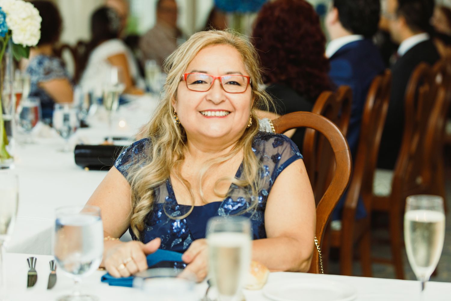 Diners enjoy a festive meal at tables decorated with blue accents and glassware.