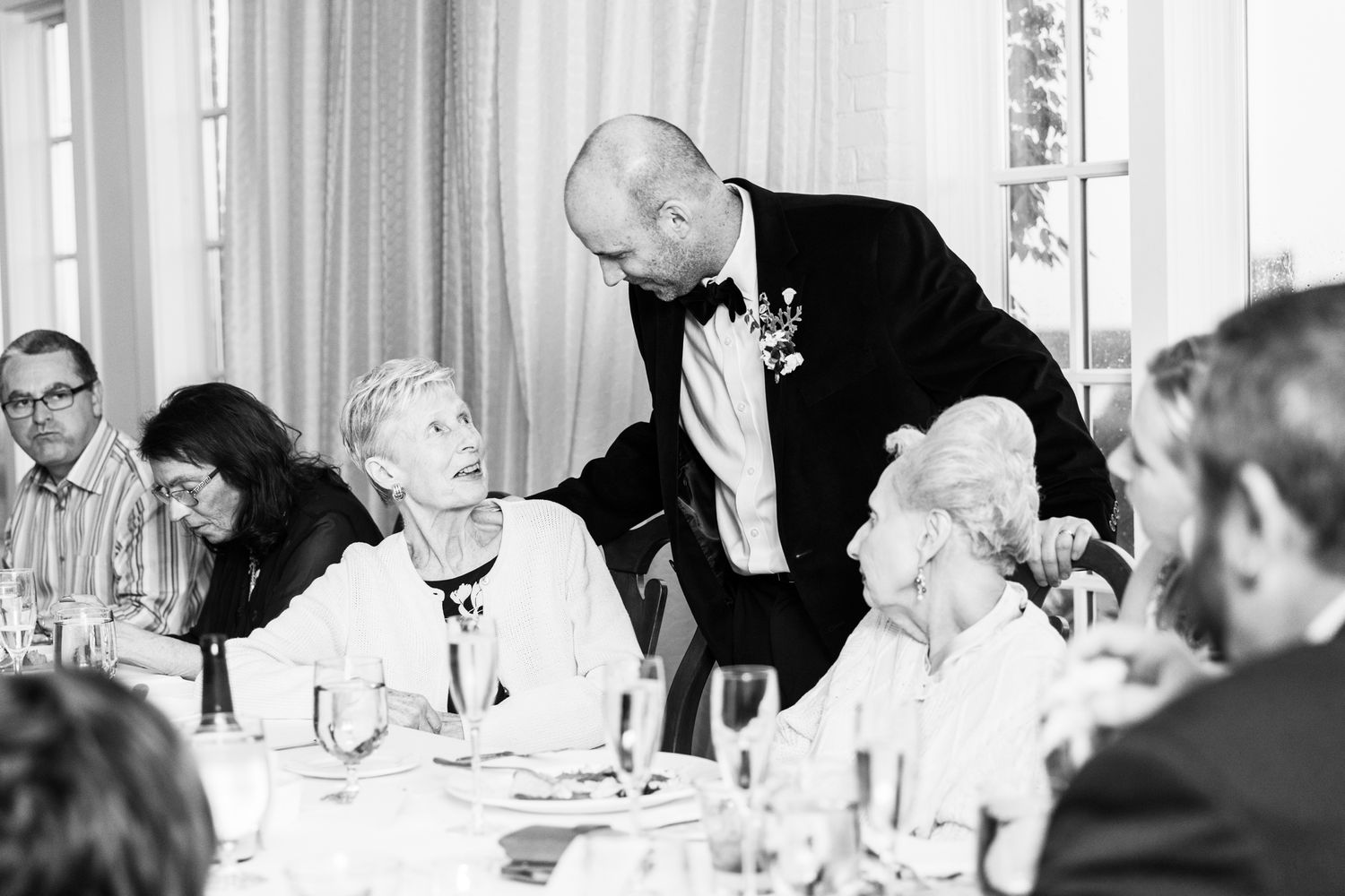 Black and white photo of guests engaged in lively dinner conversation.