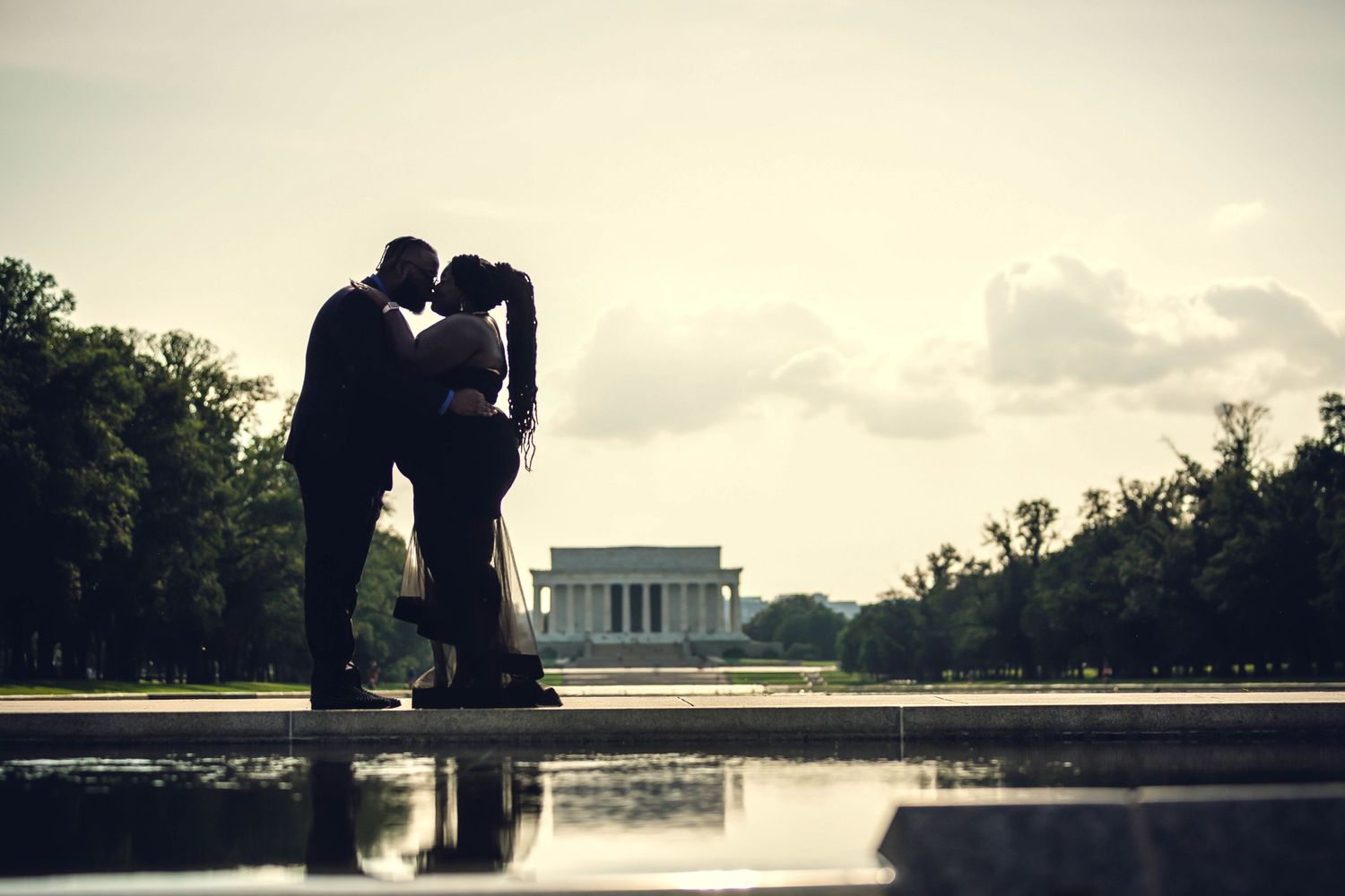 Silhouette of a couple kissing near the Reflecting Pool with the Lincoln Memorial at sunset.