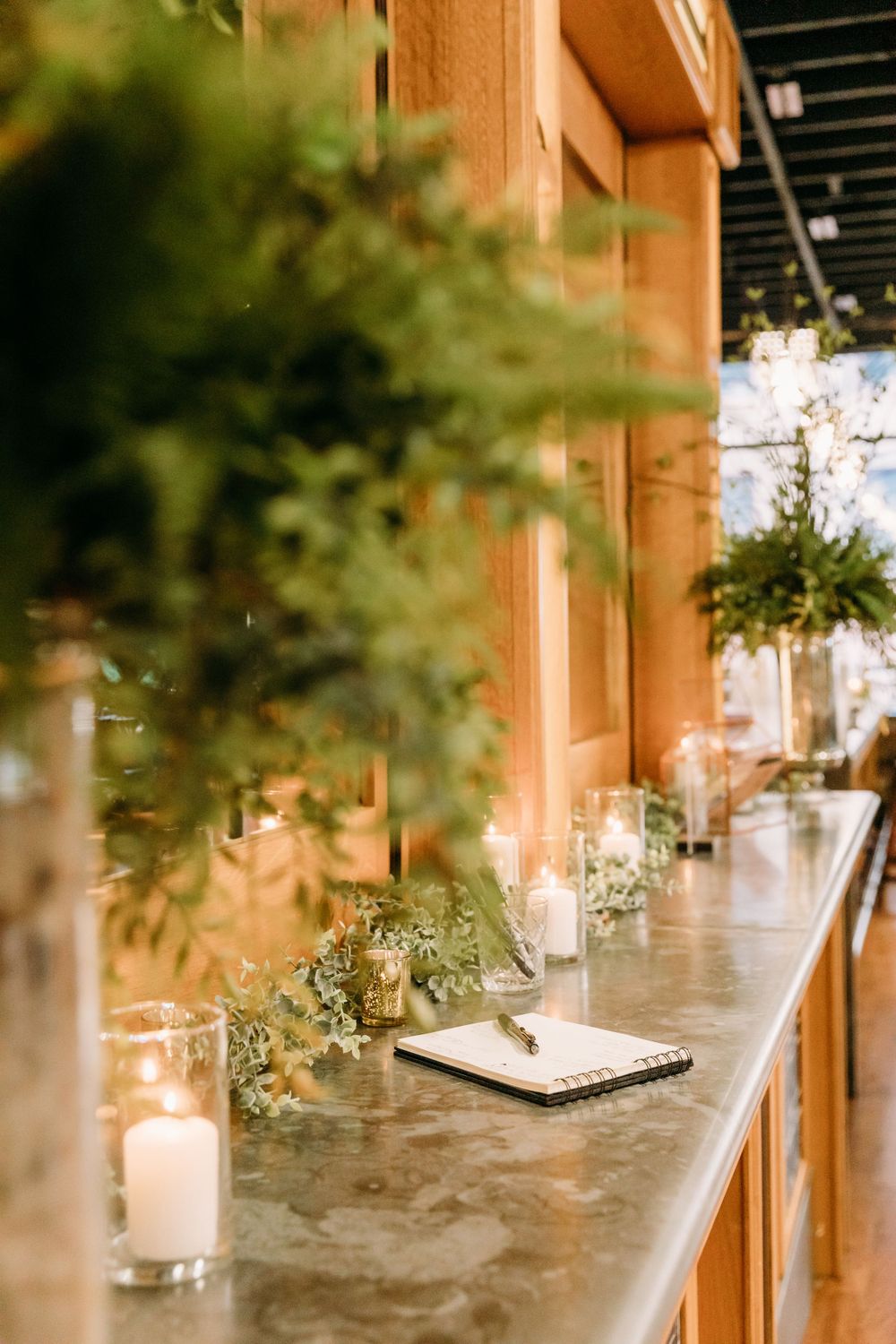 Elegant table decorations with greenery and candles against blurred background.